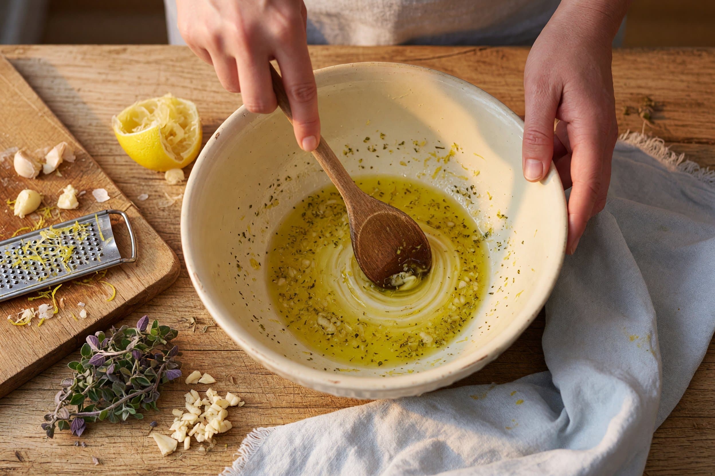Stirring lemon juice, zest, olive oil, garlic, and oregano while preparing Greek Lemon Chicken and Potatoes
